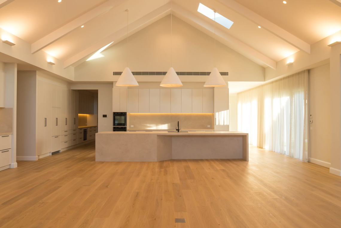 Open-plan kitchen and living area under a vaulted ceiling with skylight and full-height windows