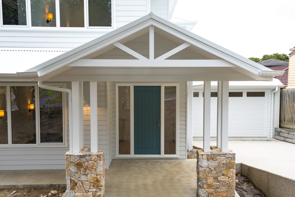 Entry porch with stone piers and white aluminium windows beside the front door, Ringwood North