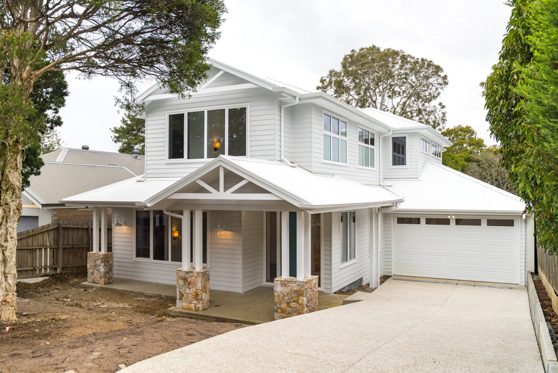 Two-storey white weatherboard home in Ringwood North with white aluminium awning windows and a gabled entry porch